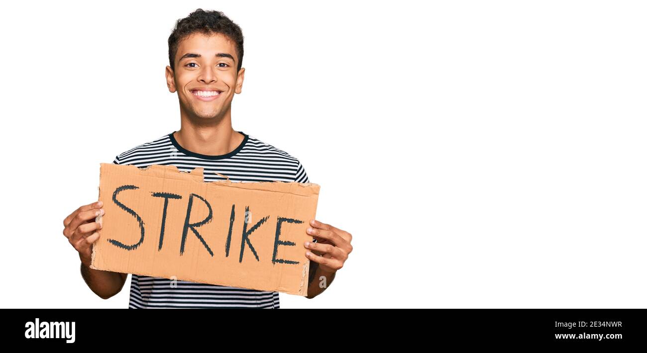 Young handsome african american man holding strike banner cardboard ...