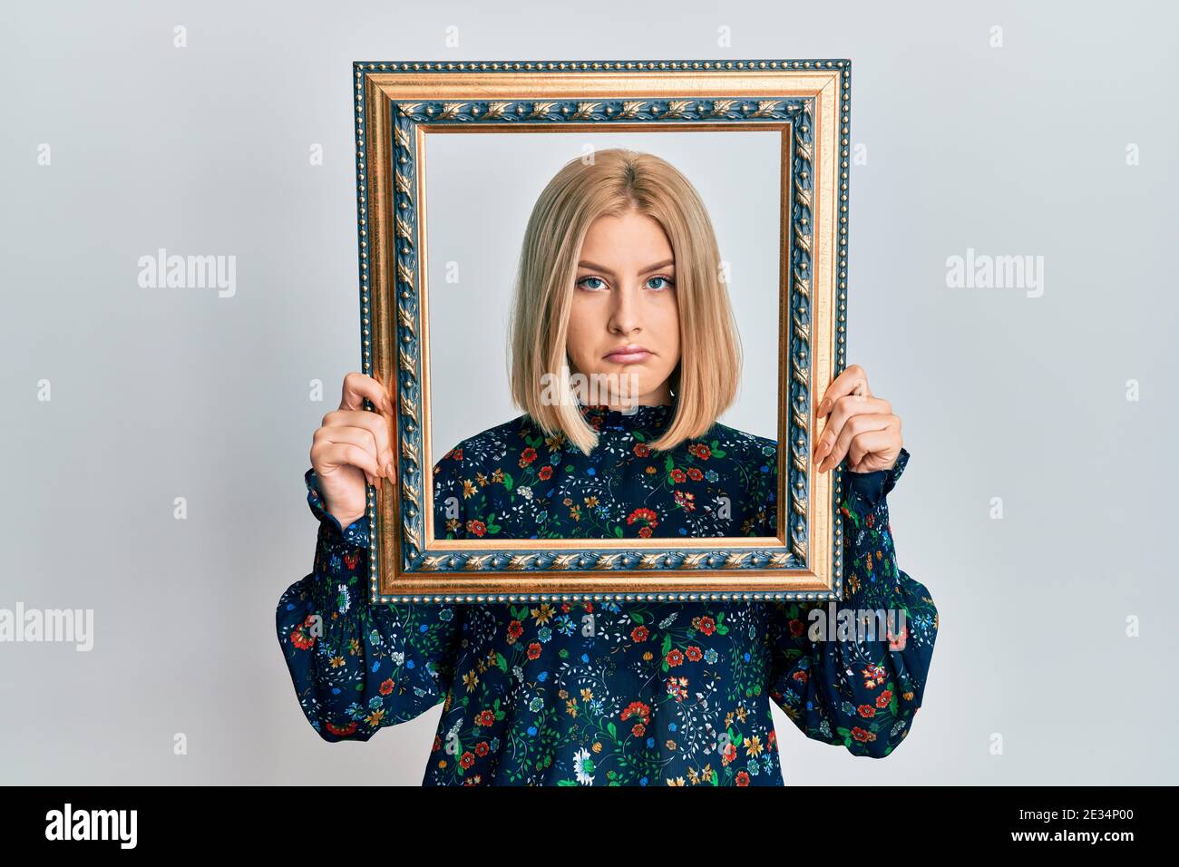 Young blonde woman holding empty frame depressed and worry for distress ...