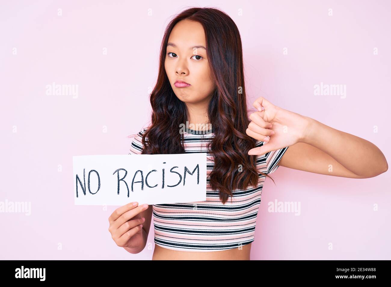 Young beautiful chinese girl holding no racism banner with angry face ...