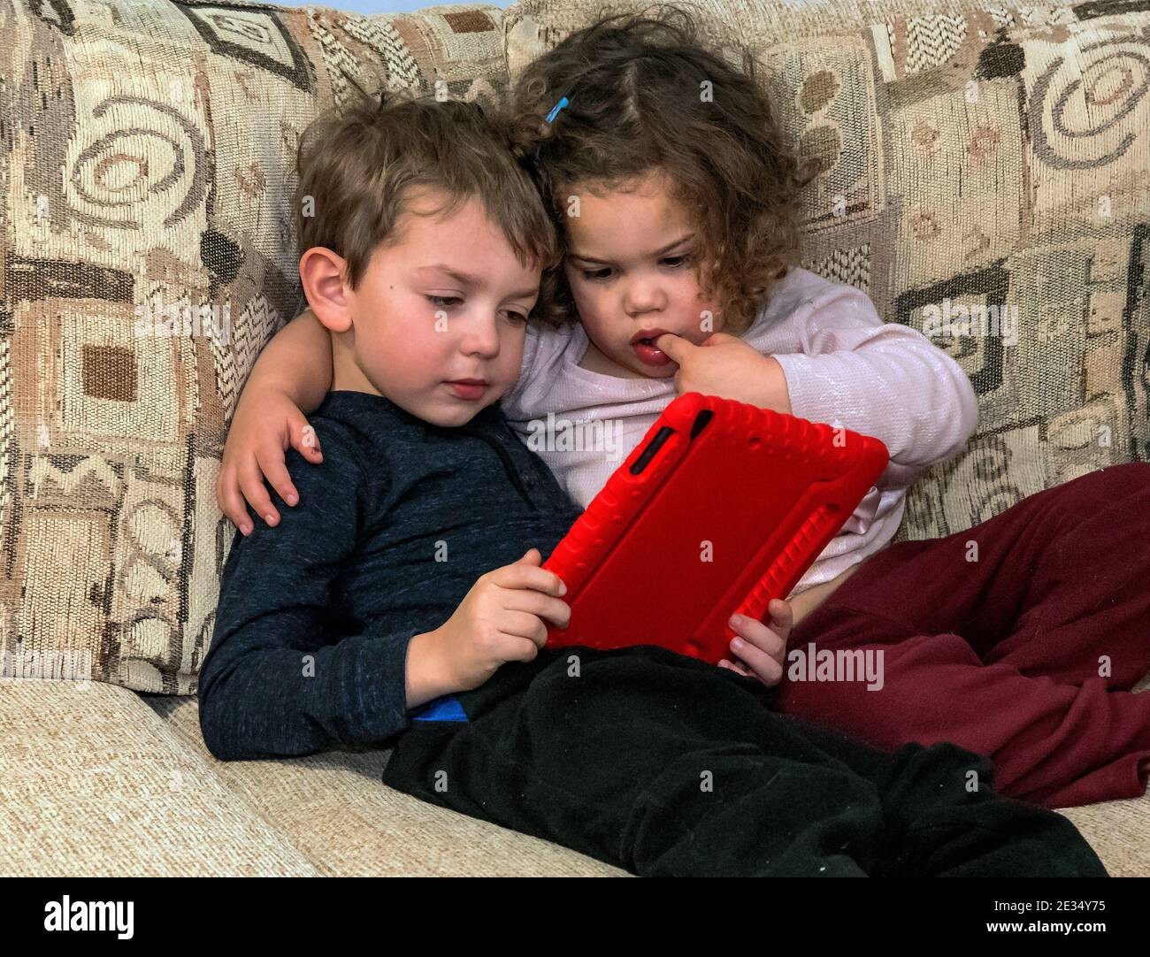 Brother and sister with tablet sit on sofa Stock Photo - Alamy