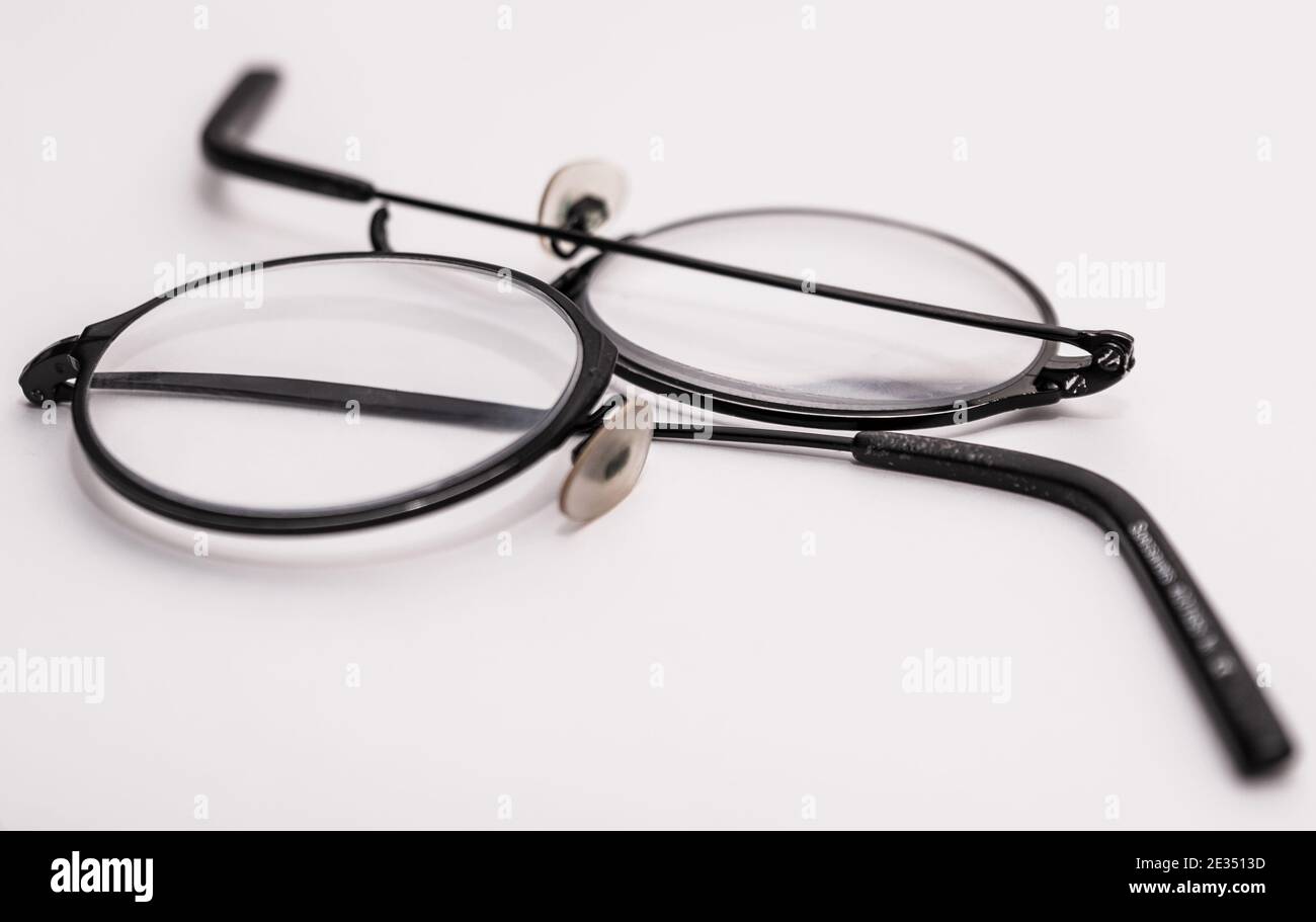 Broken glasses upon a white background. Thin round spectacles snapped at the bridge. Stock Photo