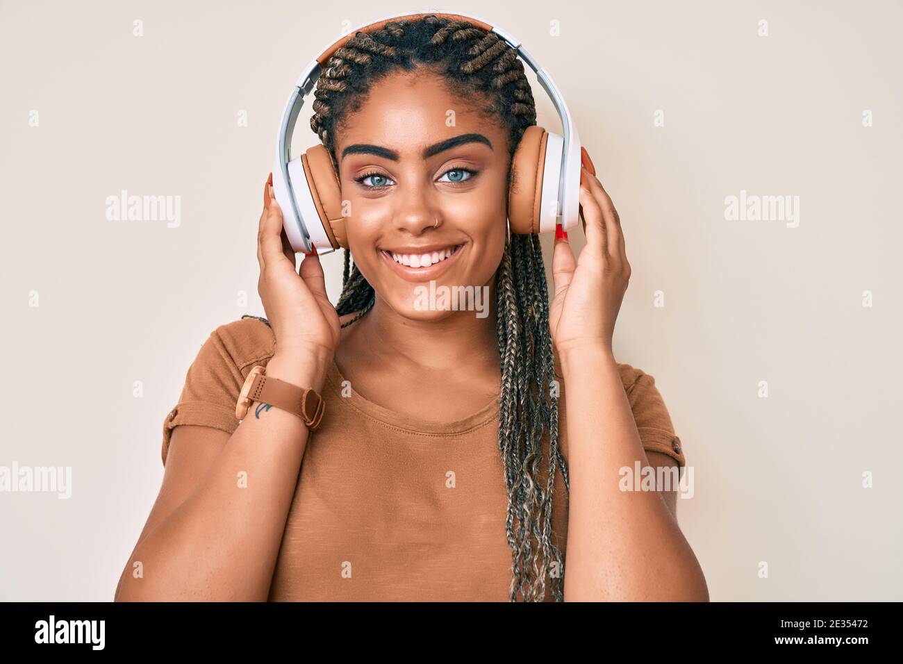 Young african american woman with braids listening to music using ...
