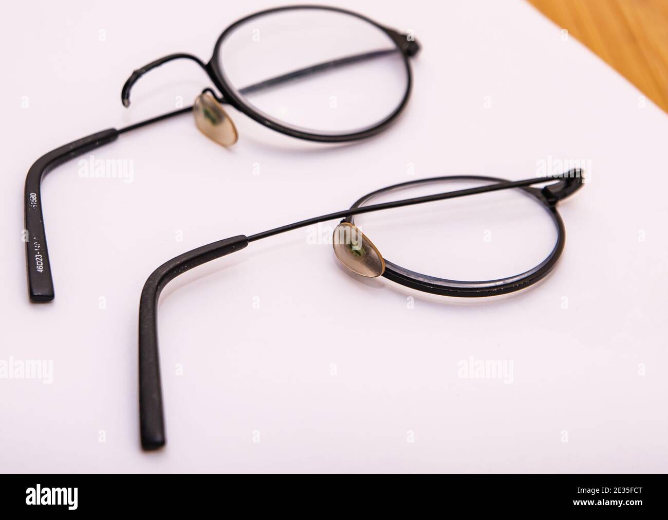 Broken glasses upon a white background. Thin round spectacles snapped at the bridge. Stock Photo