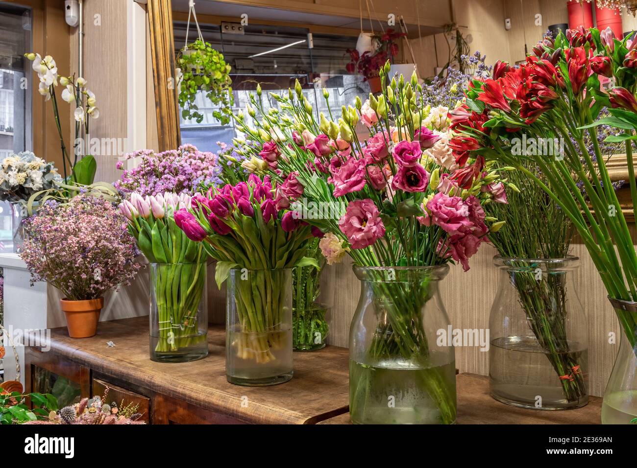 Assortment of beautiful flowers in shop for sale, placed in vases in flower shop. Tulips, roses and limonium Stock Photo