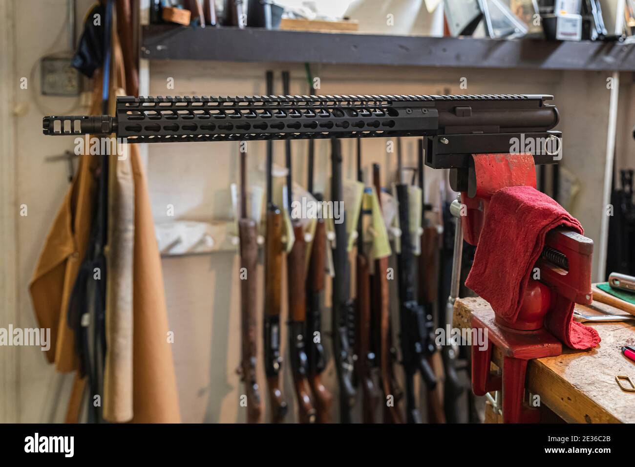 300 Blackout AR rifle upper receiver in a vise on a working table at a gun shop in California, blurred rifles in the background Stock Photo