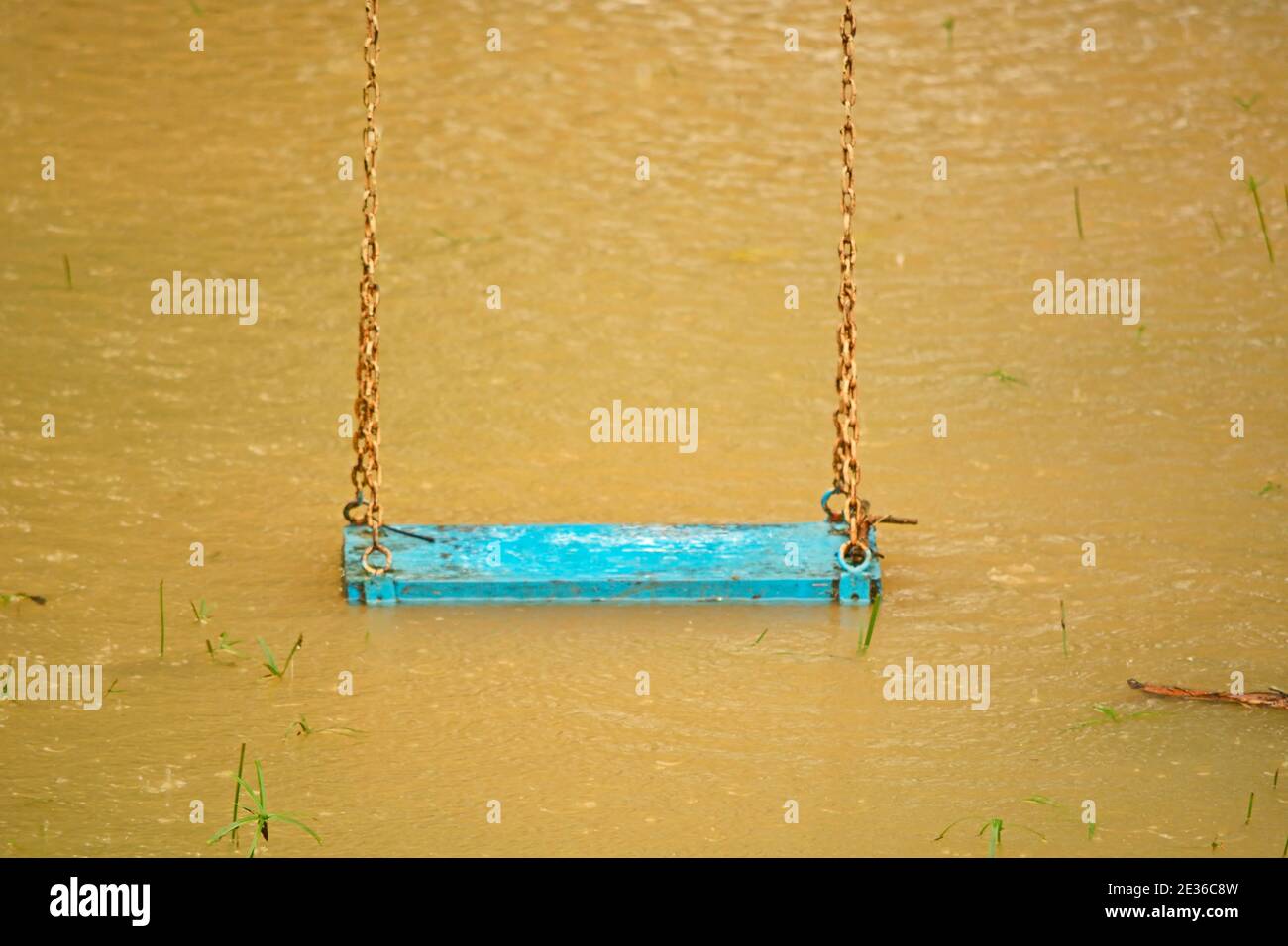 Playground swings with flooded ground and grass underneath Stock Photo