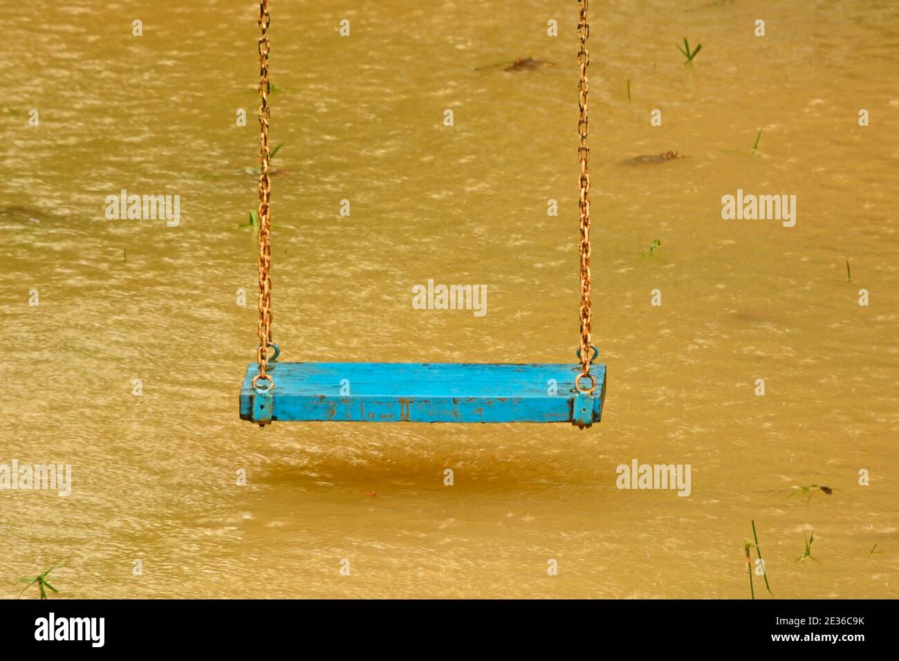 Playground swings with flooded ground and grass underneath Stock Photo