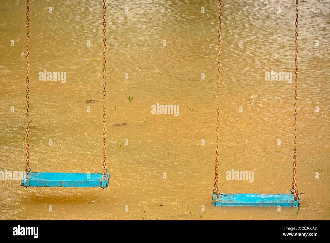 Playground swings with flooded ground and grass underneath Stock Photo