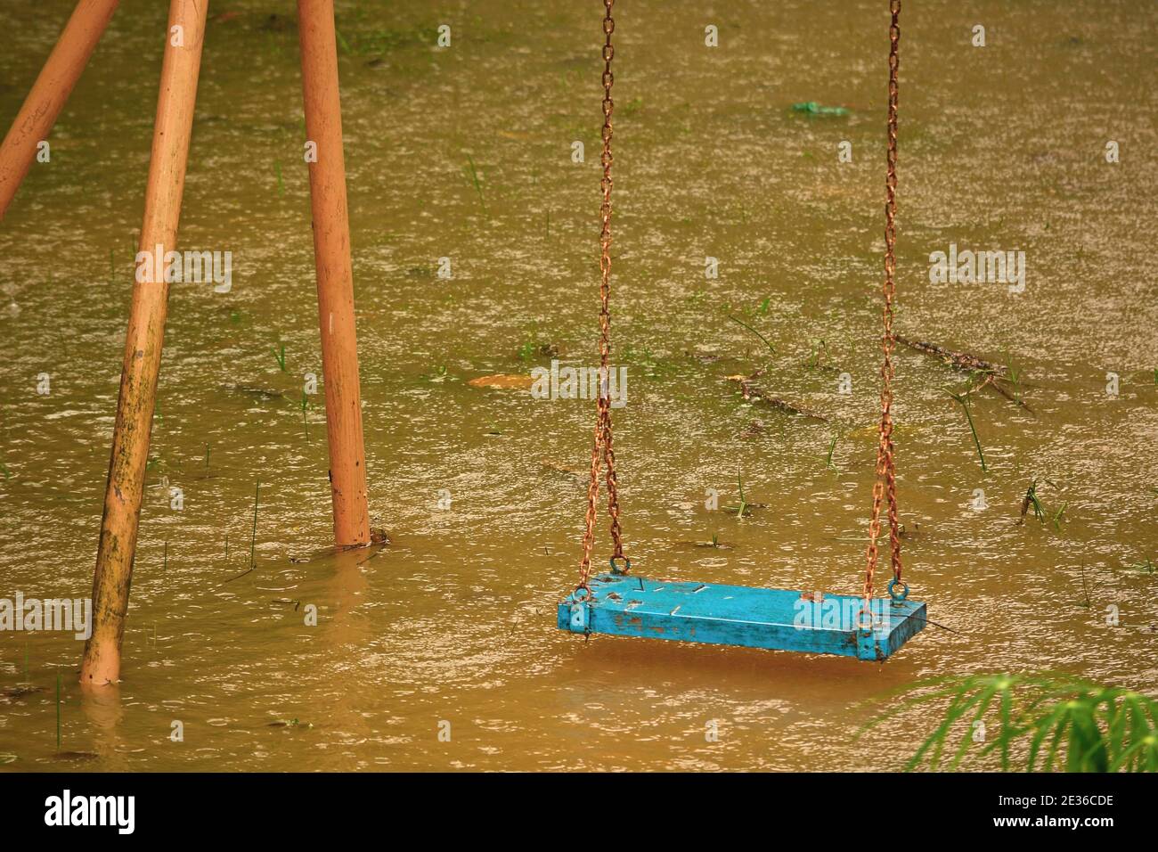 Playground swings with flooded ground and grass underneath Stock Photo
