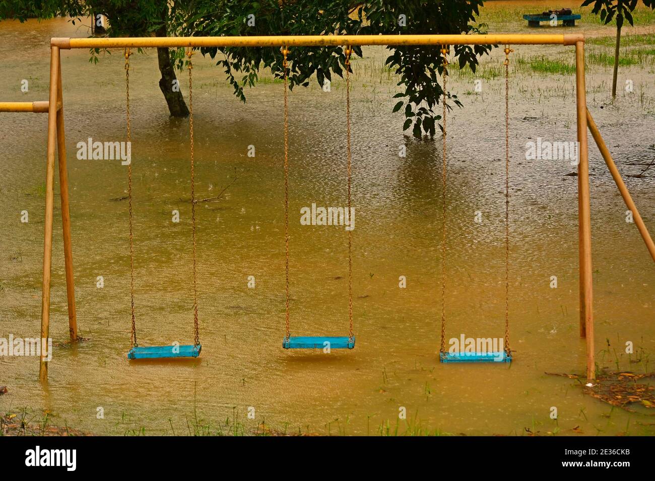 Playground swings with flooded ground and grass underneath Stock Photo