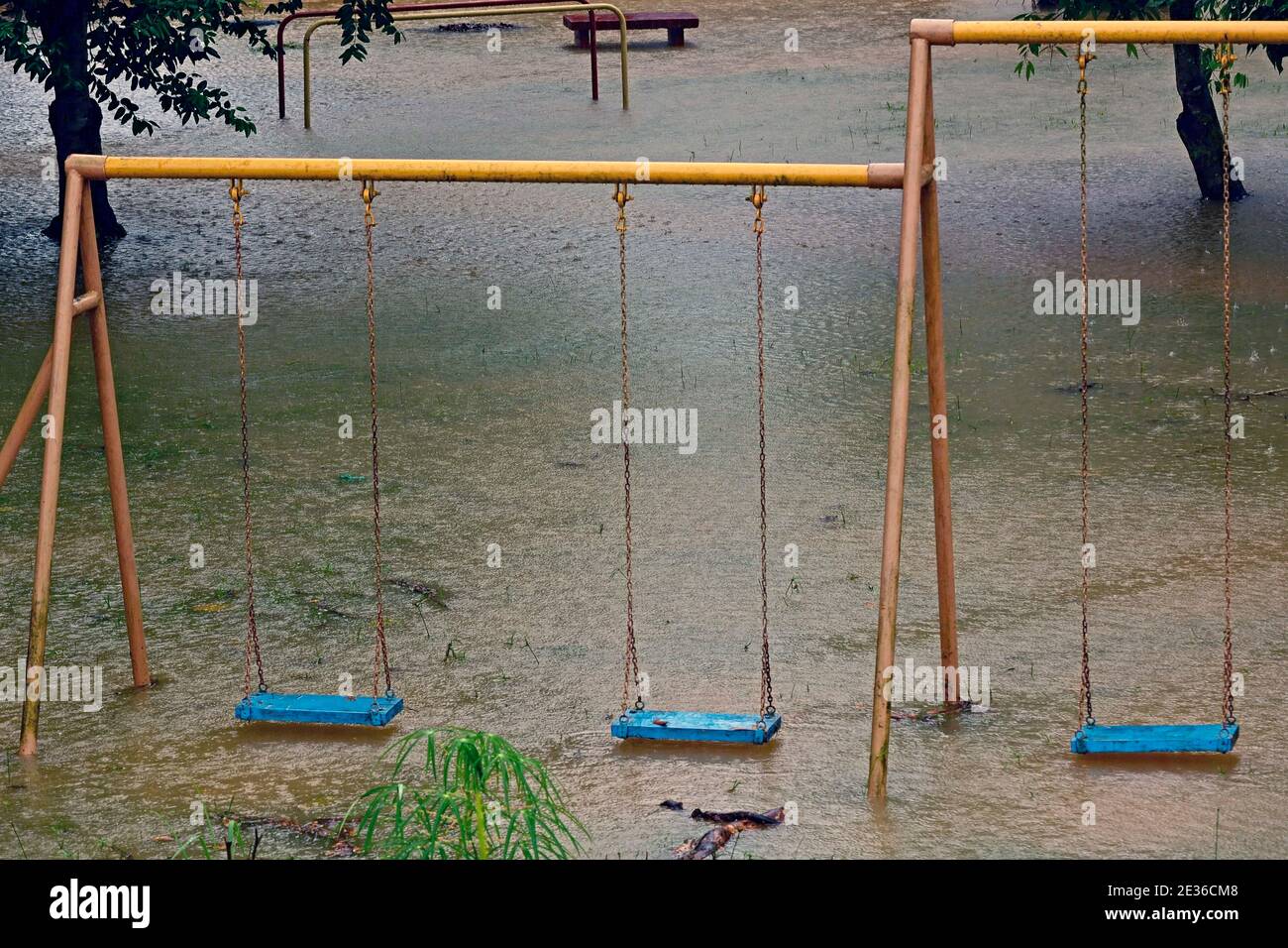 Playground swings with flooded ground and grass underneath Stock Photo