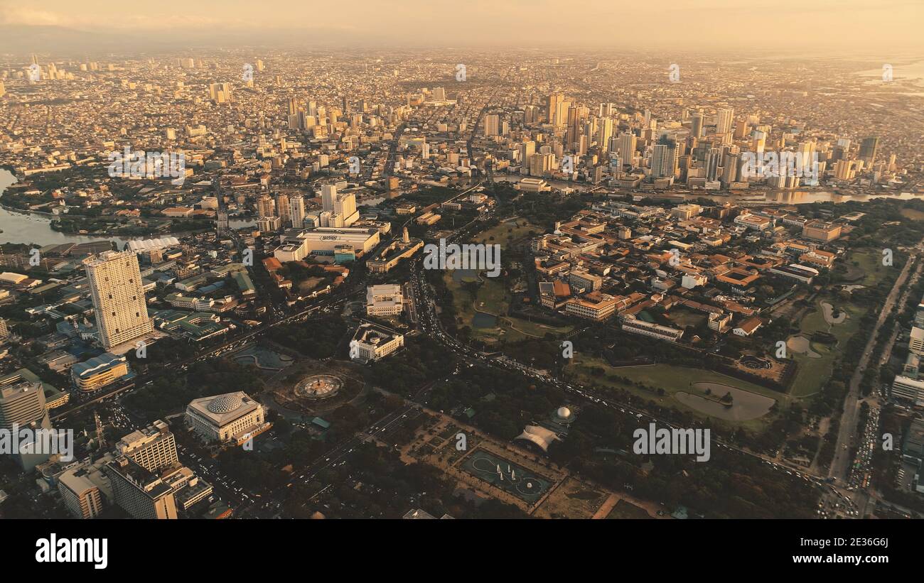 Metropolis city with designed park at river bank aerial. Downtown streets with modern buildings at sun light. Urban highway at skyscrapers, houses, cottages of Manila town, Philippines Stock Photo