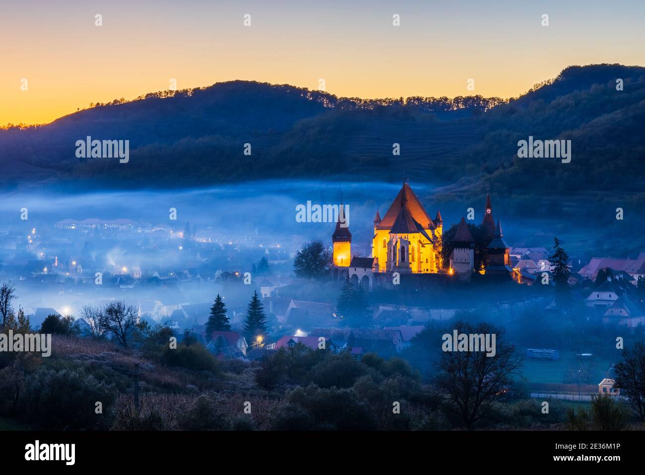 Biertan, Romania. Foggy sunset at the saxon village with the fortified church, Transylvania. Stock Photo