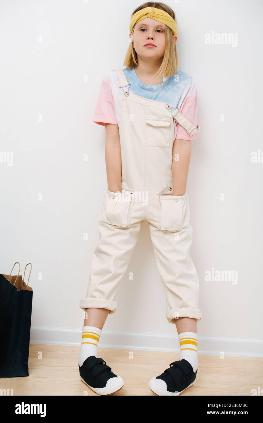 Teenage girl stands leaning on wall and hands in pockets Stock Photo