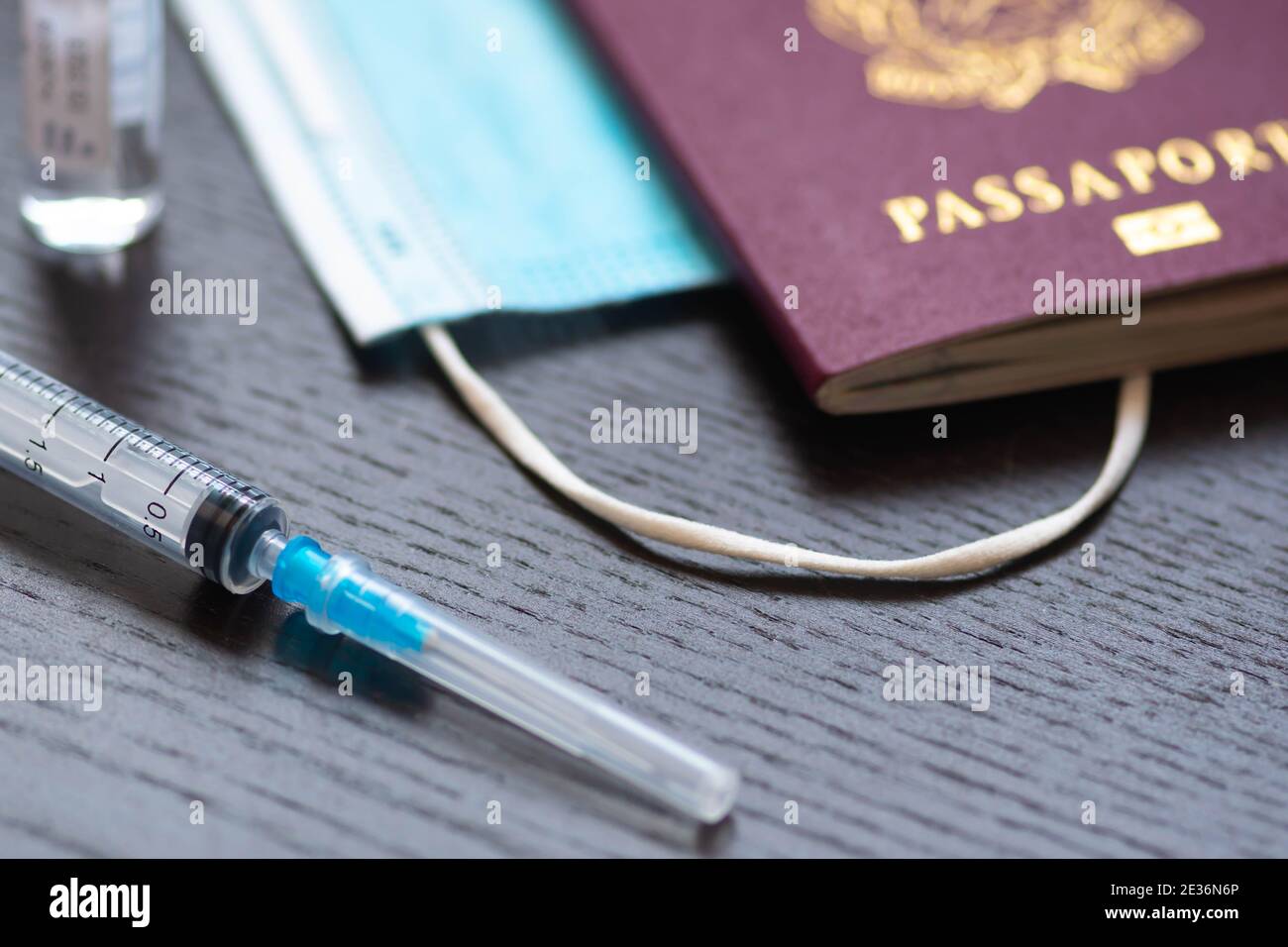 Syringe, vial, surgical face mask and passport or visa on a white table ready to be used. Covid or Coronavirus vaccine background, Covid-19 immunity p Stock Photo