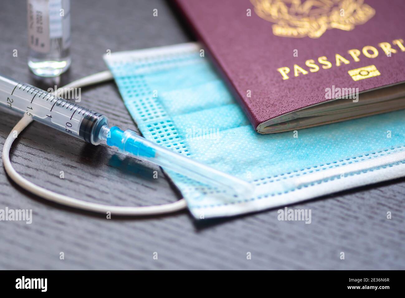 Syringe, vial, surgical face mask and passport or visa on a white table ready to be used. Covid or Coronavirus vaccine background, Covid-19 immunity p Stock Photo