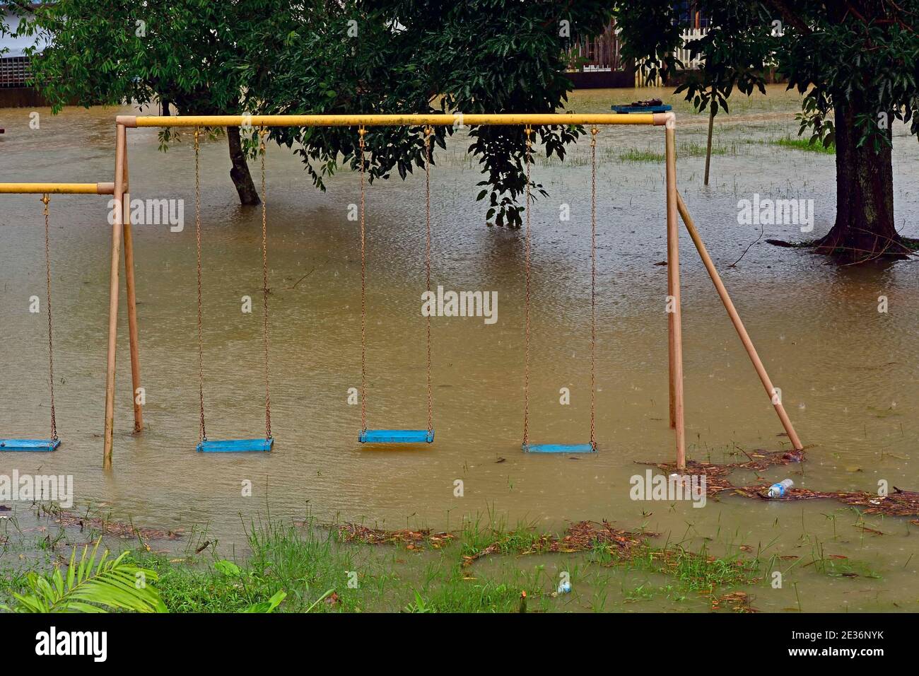 Playground swings with flooded ground and grass underneath Stock Photo