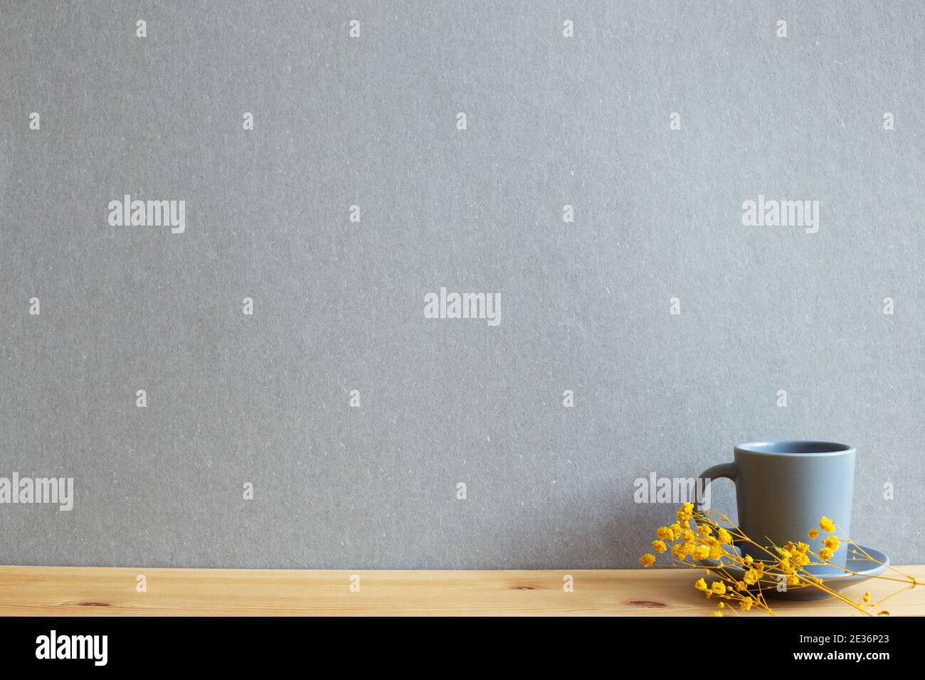 Coffee cup with yellow gypsophila dry flowers on wooden table. gray background Stock Photo
