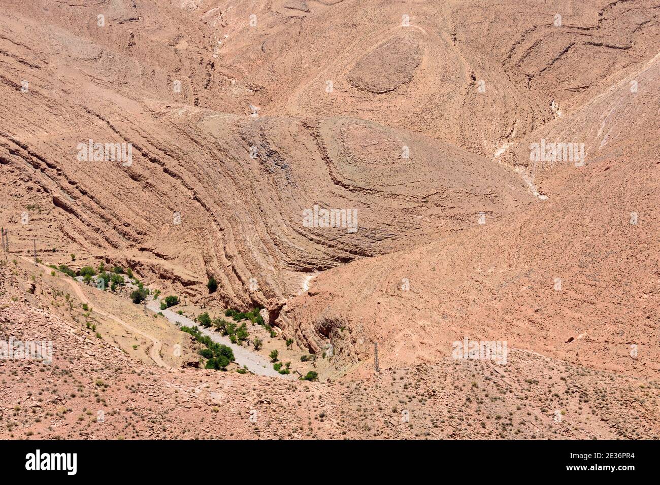 Aerial view of a dry riverbed and a dirtroad between geological formations in the High Atlas, Morocco. Stock Photo
