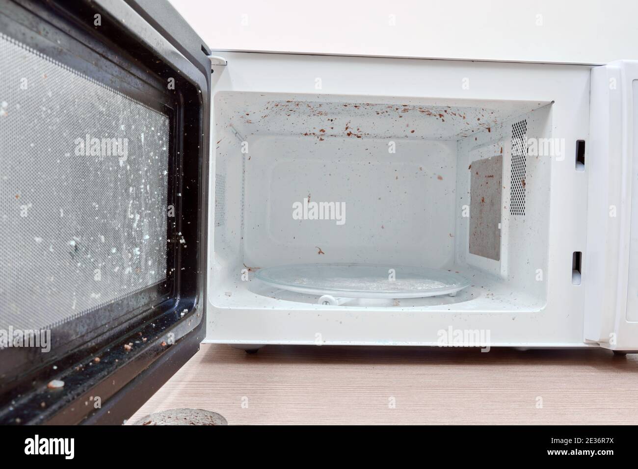 A dirty microwave oven with an open door in need of washing and