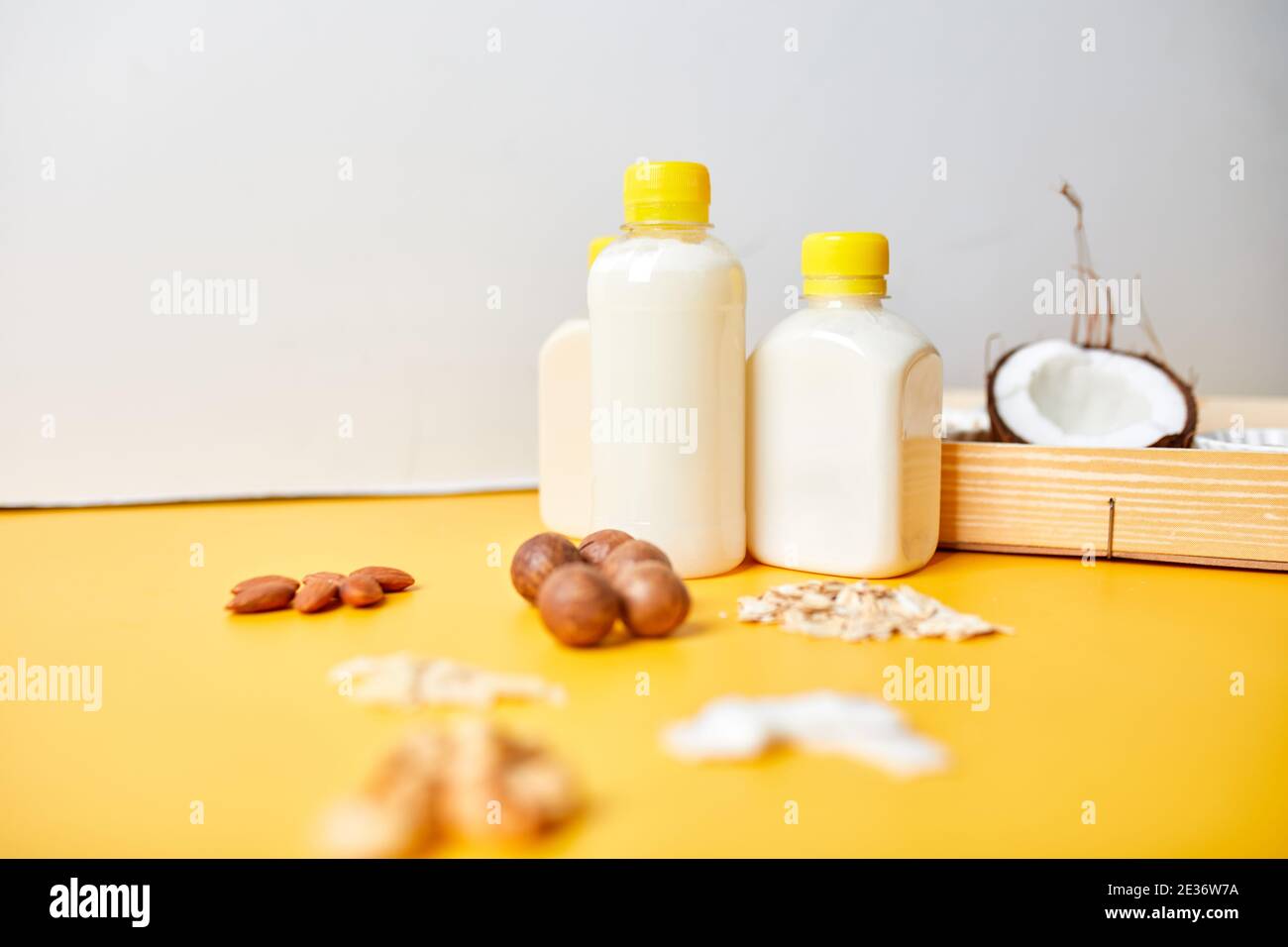 Alternative types of vegan milks in bottles on a yellow background