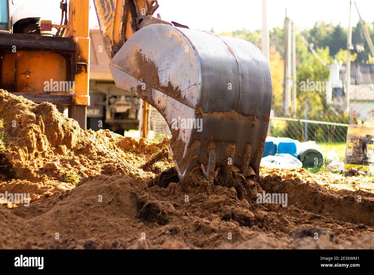 An excavator metal bucket digs sand or clay on a construction site, digging a trench. Stock Photo