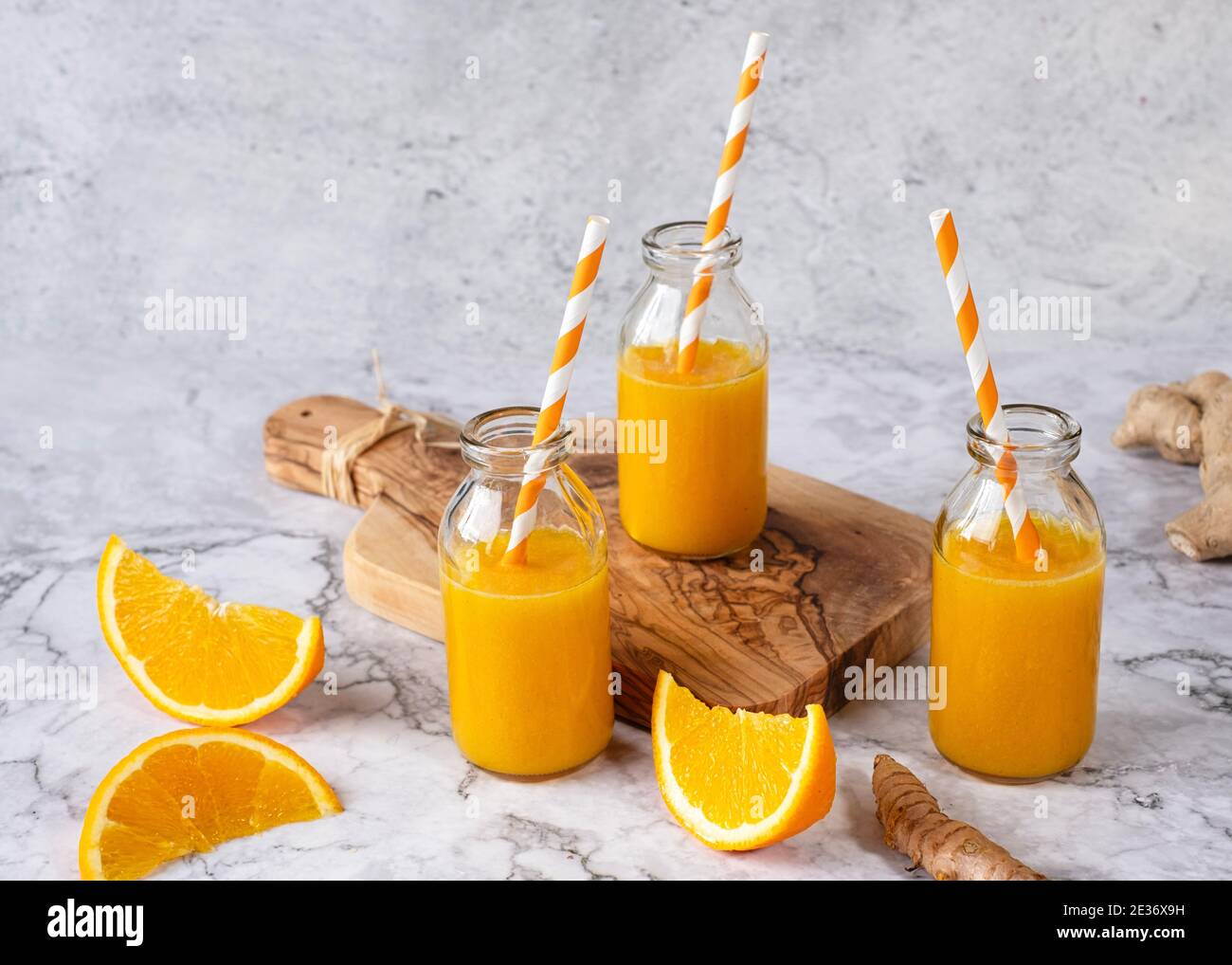 Three identical bottles filled with homemade ginger turmeric orange