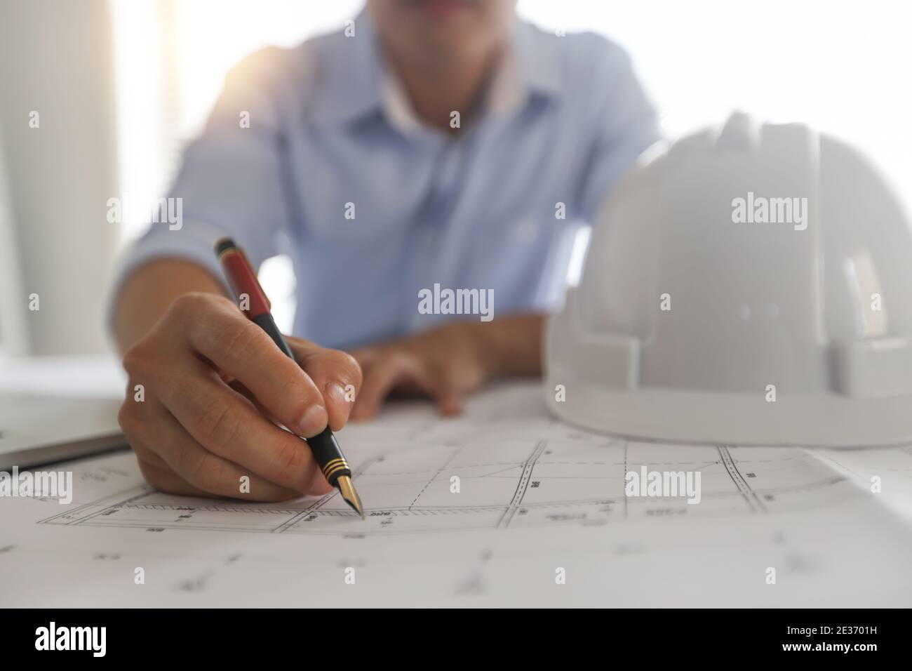 Young engineers or architect holding pen and drawing plan on blueprint