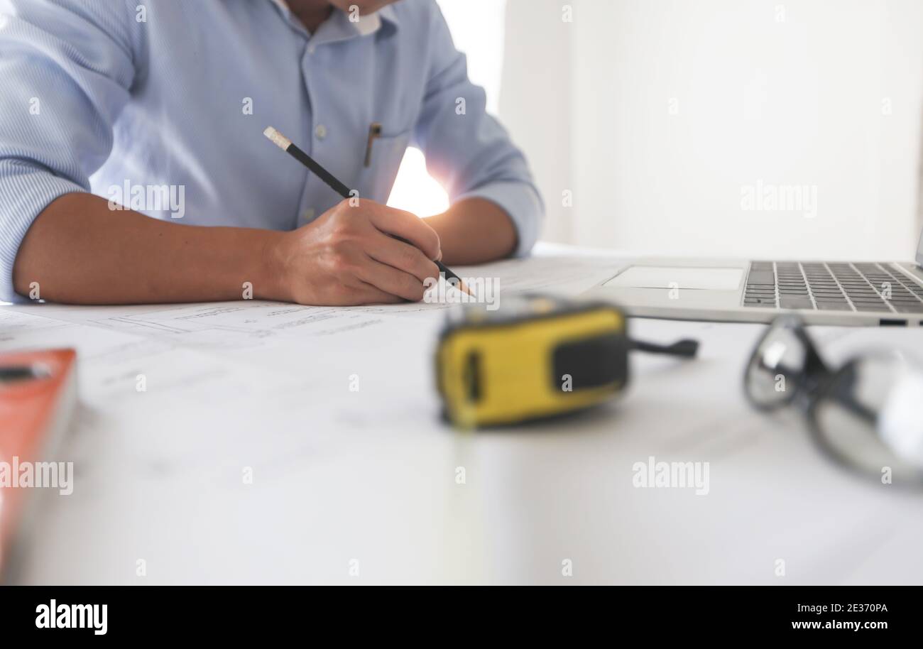 Young engineers or architect holding pen and drawing plan on blueprint