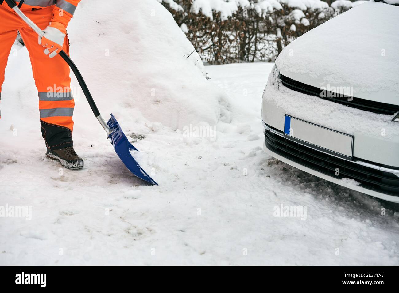 Communal service worker in uniform with a shovel clears snow in winter Stock Photo