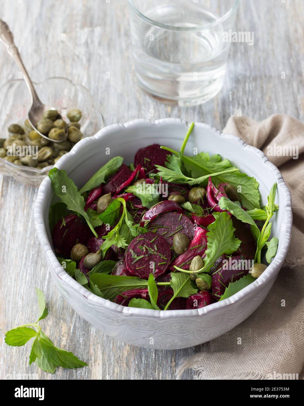 Vegan healthy beetroot salad with baked red onion, capers, watercress, greens and vinaigrette sauce on a wooden table. Delicious homemade food Stock Photo