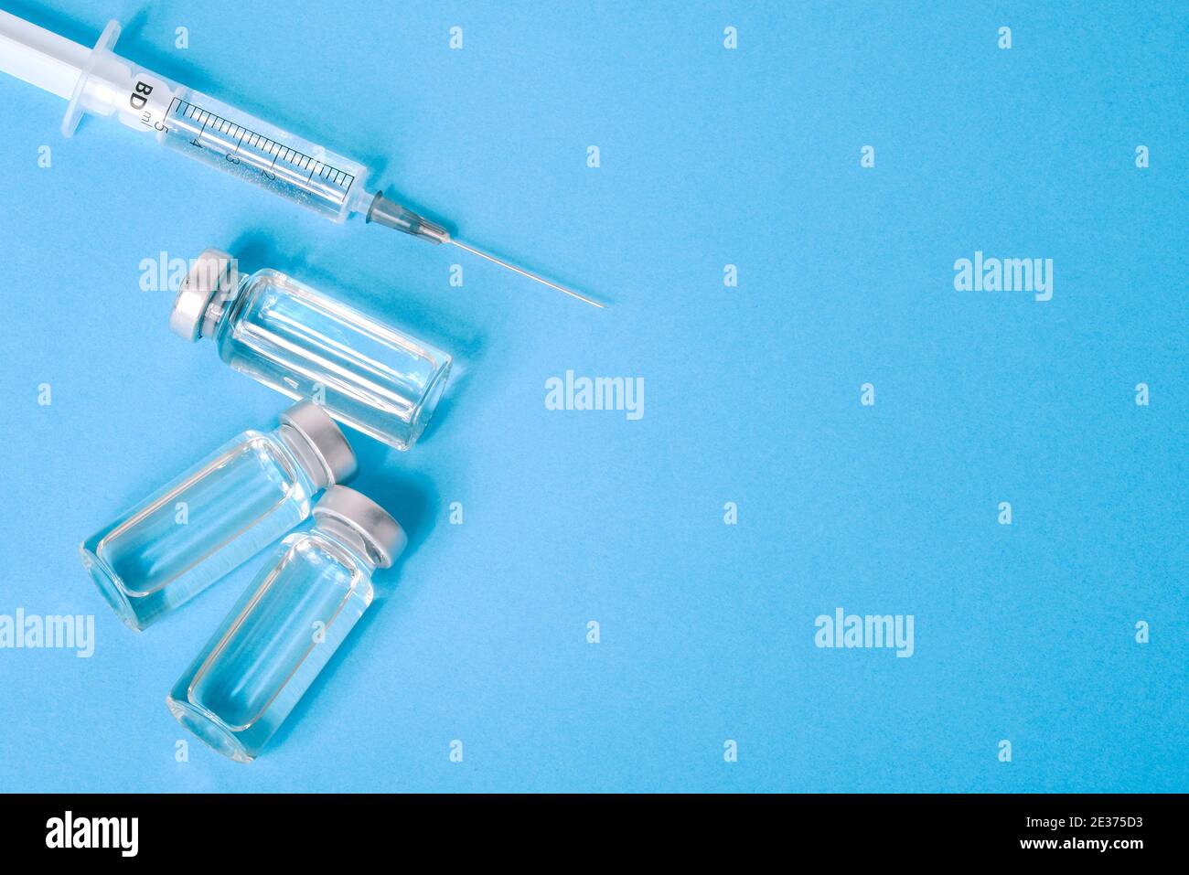 Covid vaccine and medical syringe on blue background with copy space ...