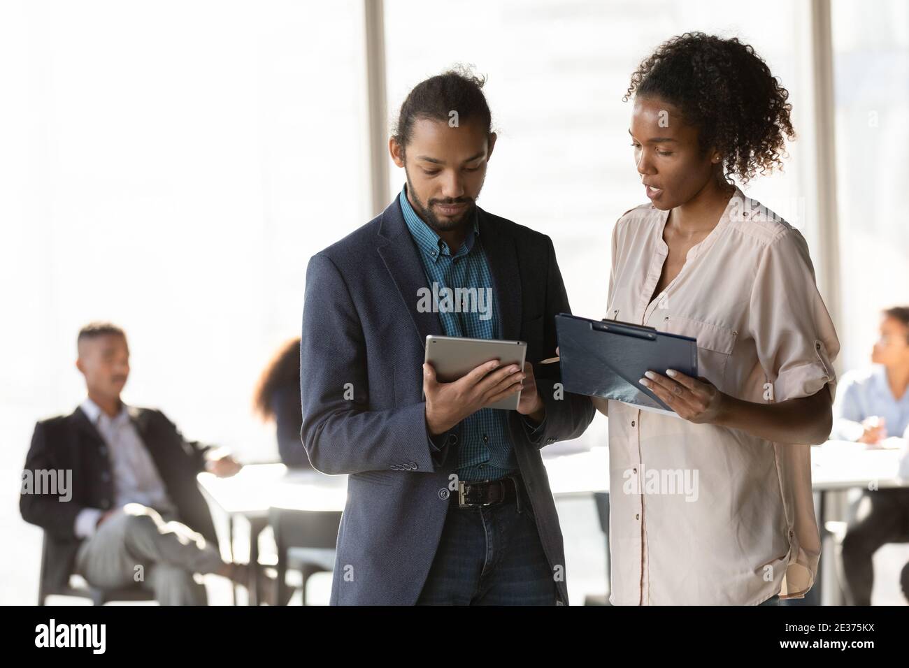 Multiracial diverse employees brainstorm together using tablet Stock Photo