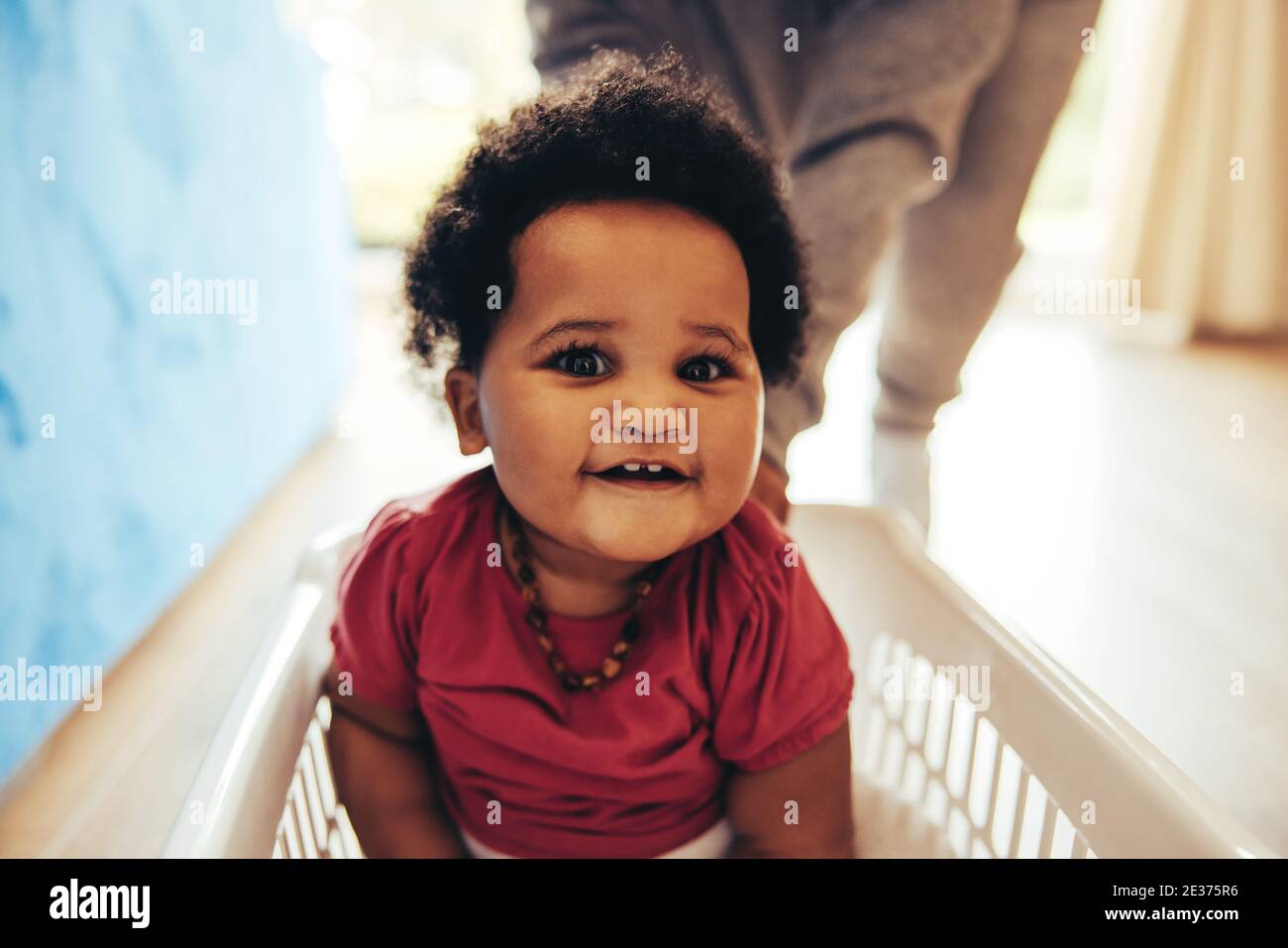 Baby sitting in a washing basket being pushed by woman. Cute baby