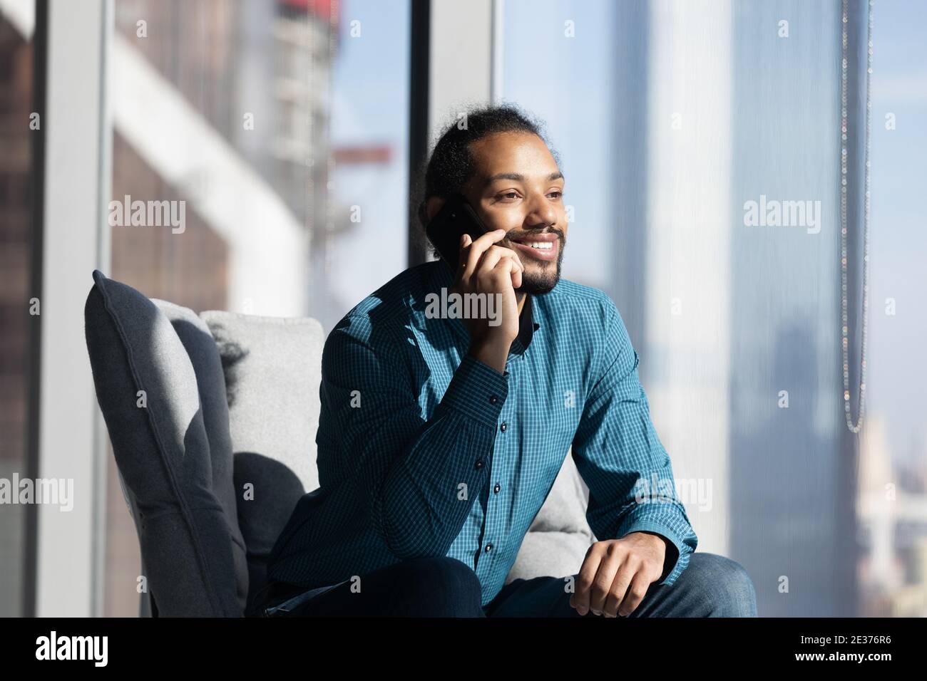 Smiling ethnic man use cellphone talking with client Stock Photo