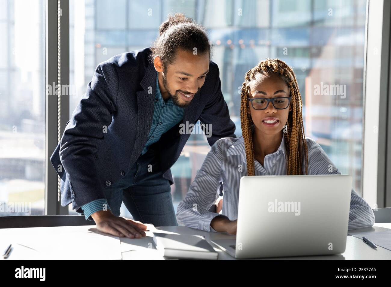 Smiling multiethnic colleagues work on laptop together Stock Photo