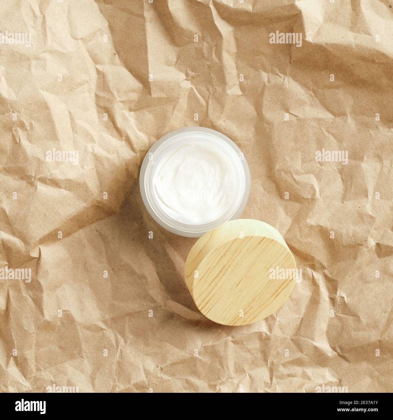 Jar of natural moisturizer face cream on kraft paper top view. Eco