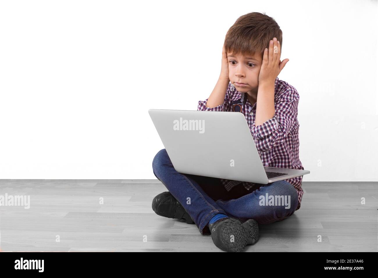 boy with laptop with shocked face puts his hands to his head Stock Photo