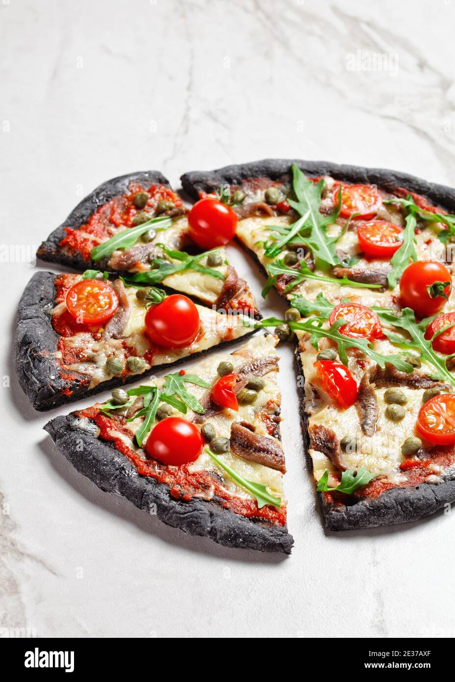 black dough pizza with anchovy, melted mozzarella cheese, tomato
