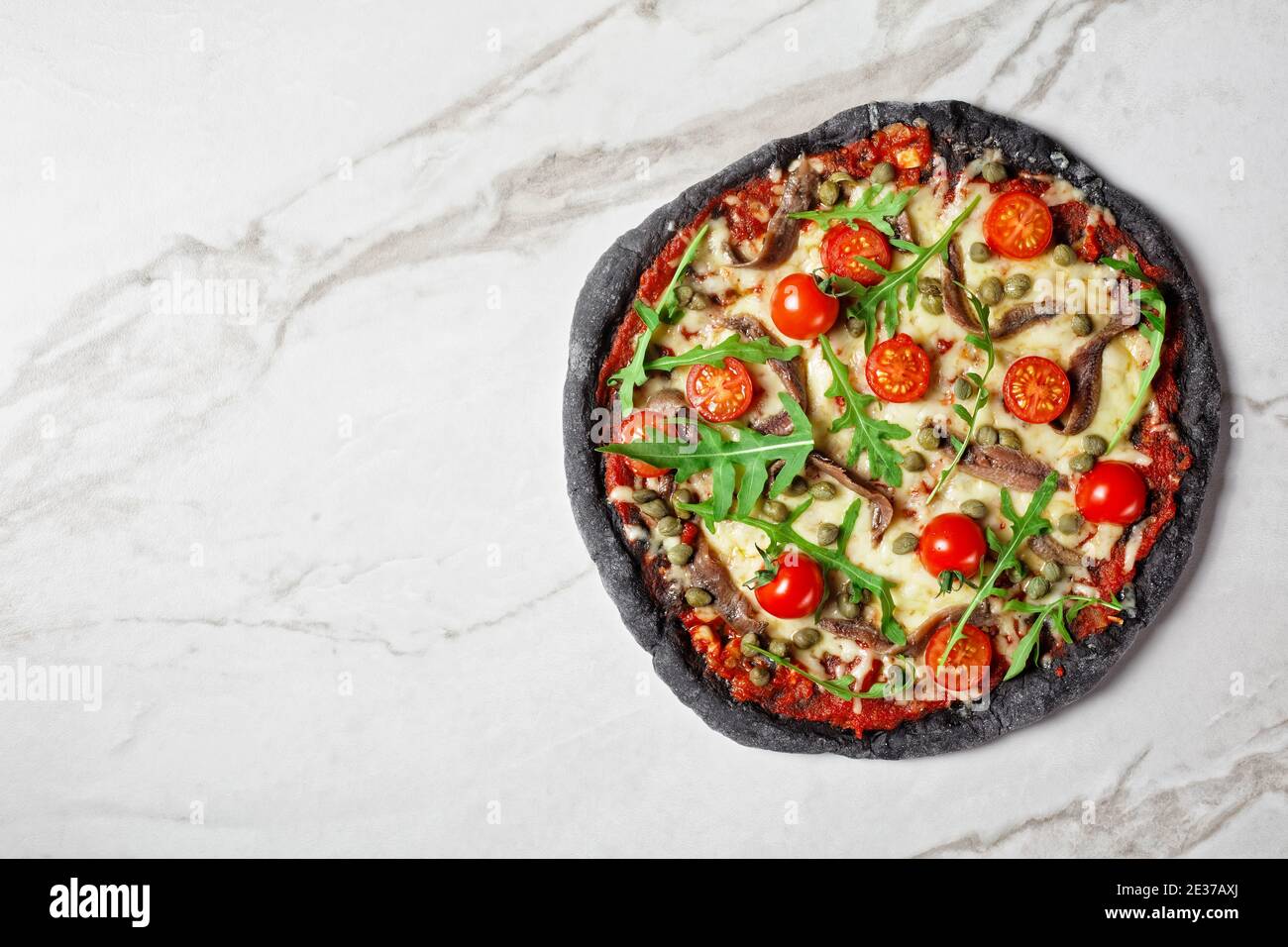 black dough pizza with anchovy, melted mozzarella cheese, tomato