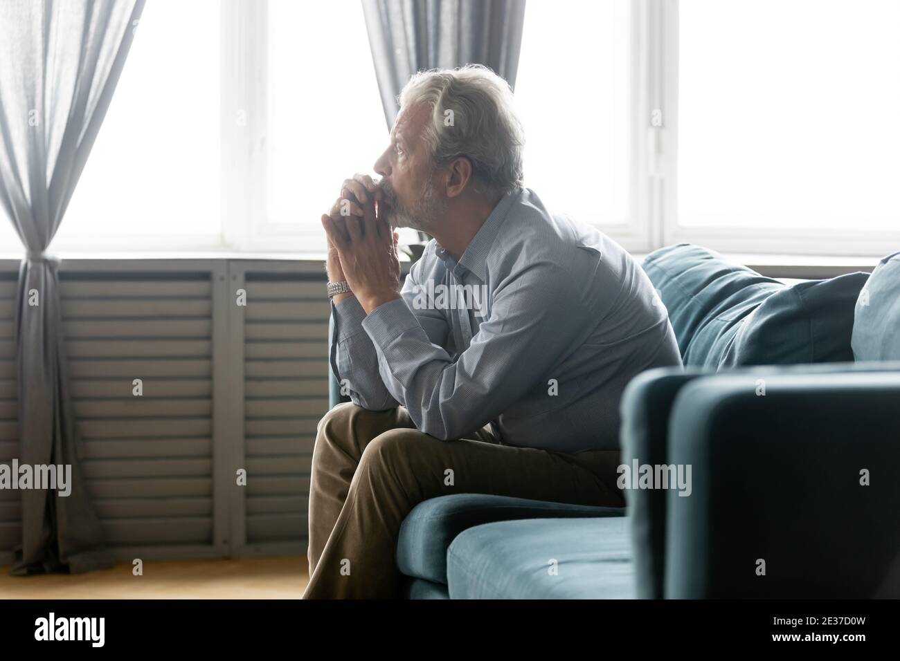 Unhappy middle aged grandfather lost in thoughts alone at home. Stock Photo