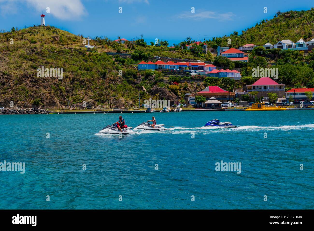 Gustavia, St Barths-- April 25, 2018. Man and woman pilot jet skis in Gustavia while towing an empty one behind them. Editorial Use Only. Stock Photo
