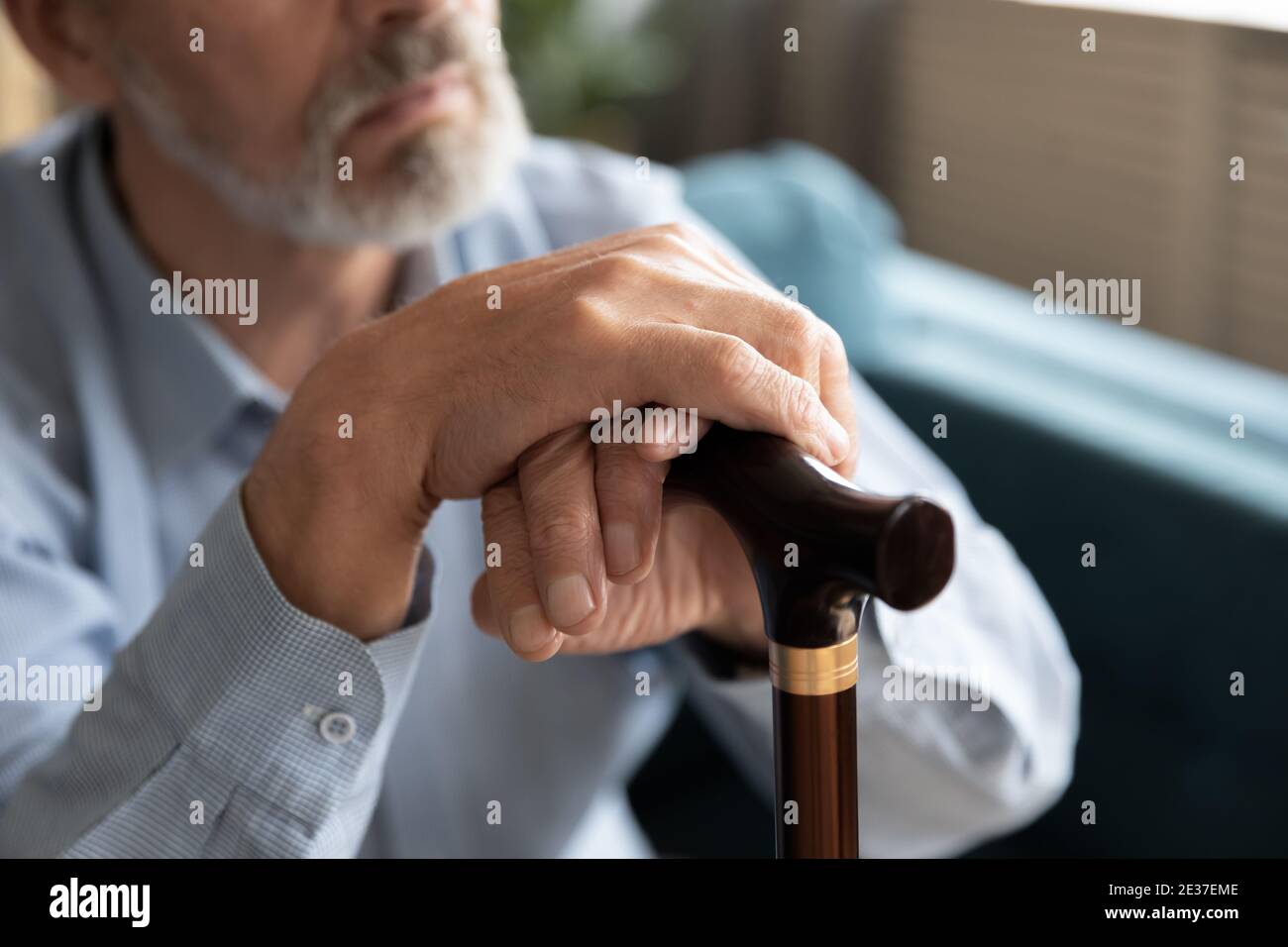 Thoughtful middle aged disabled grandfather resting on sofa. Stock Photo