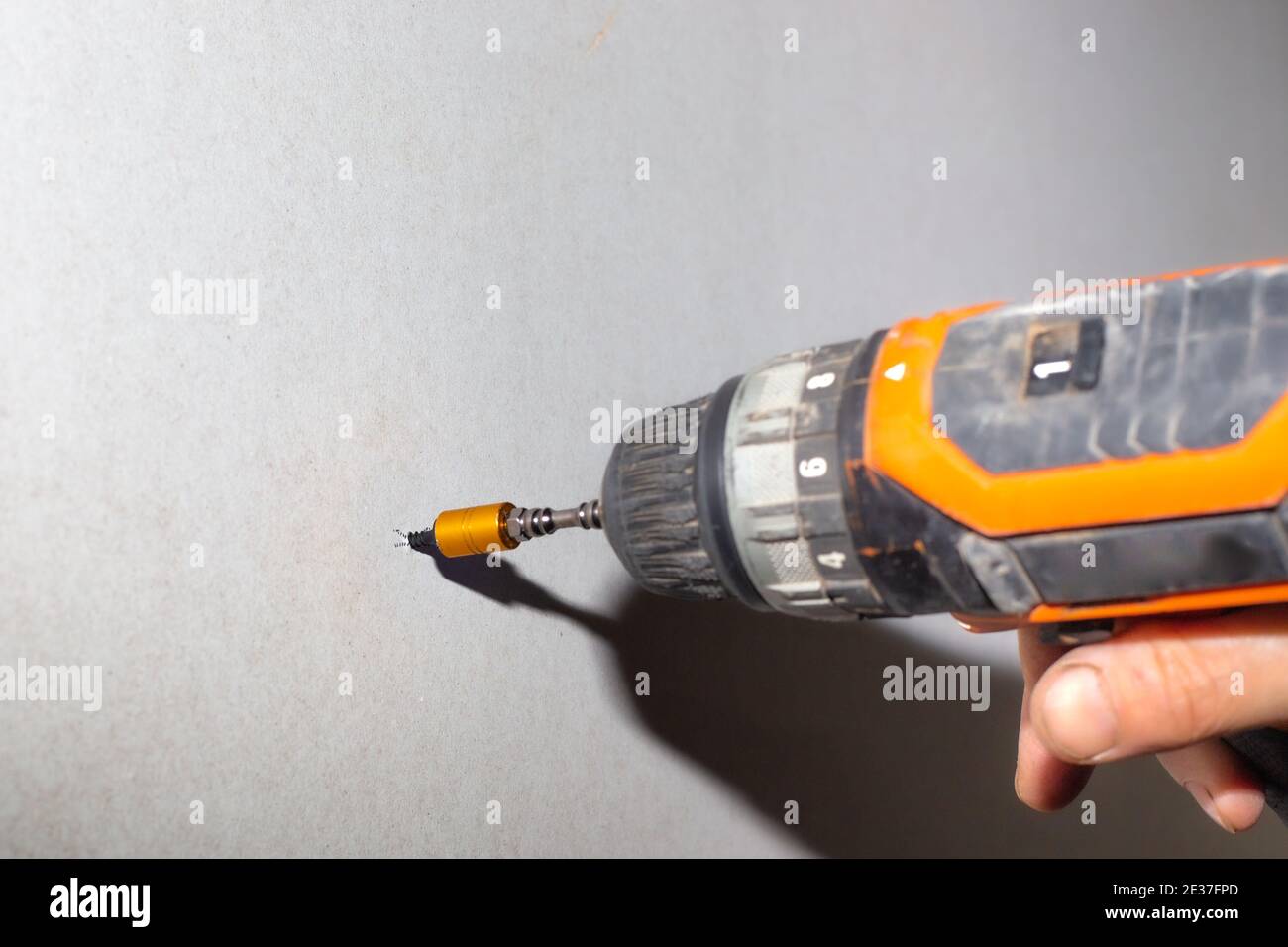 A man uses a screwdriver to screw a screw into a drywall. Home renovation, wall cladding. Stock Photo