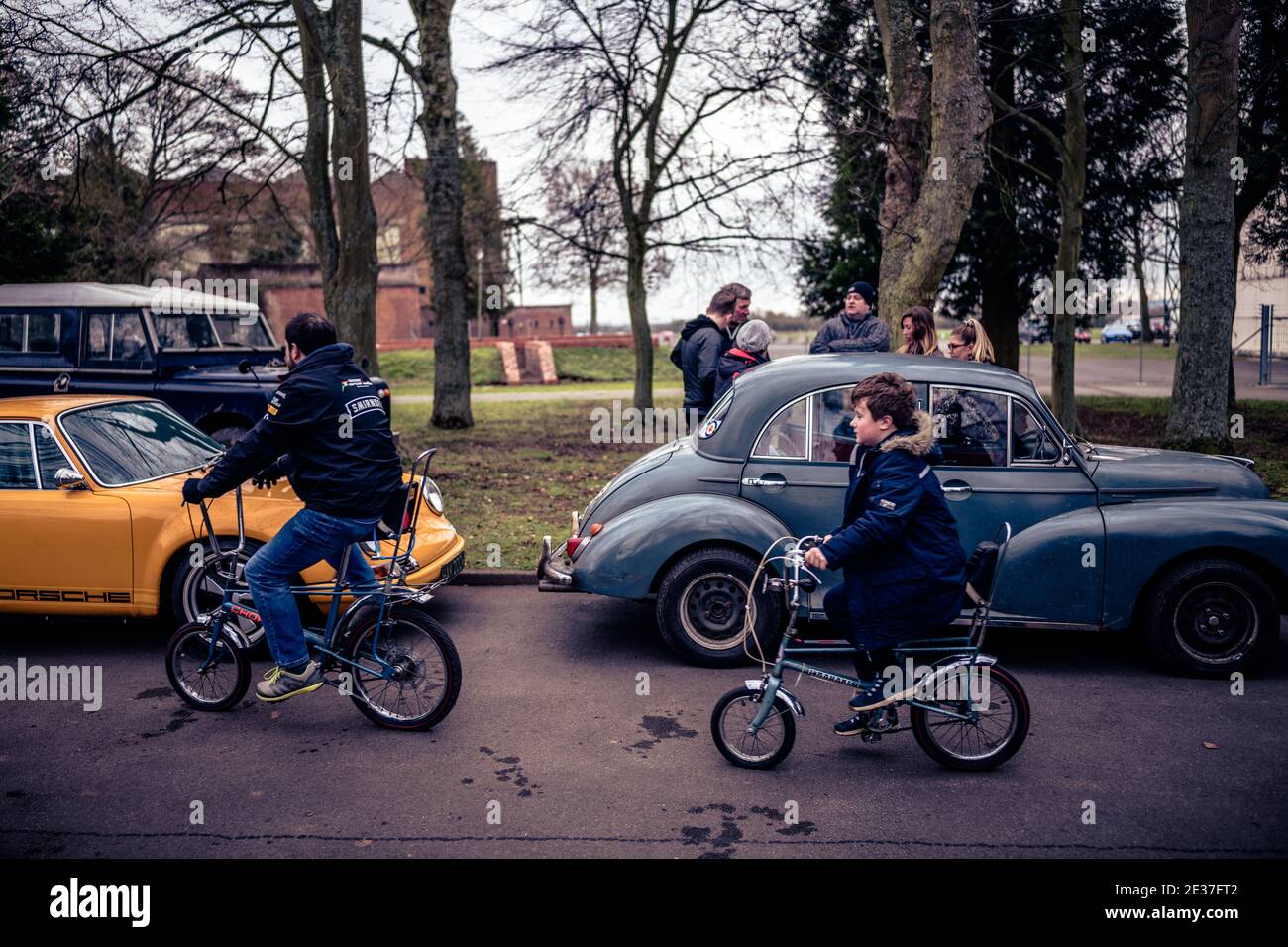 An adult and child ride past on Raleigh Chopper bicycles at an open day at Bicester Heritage Stock Photo