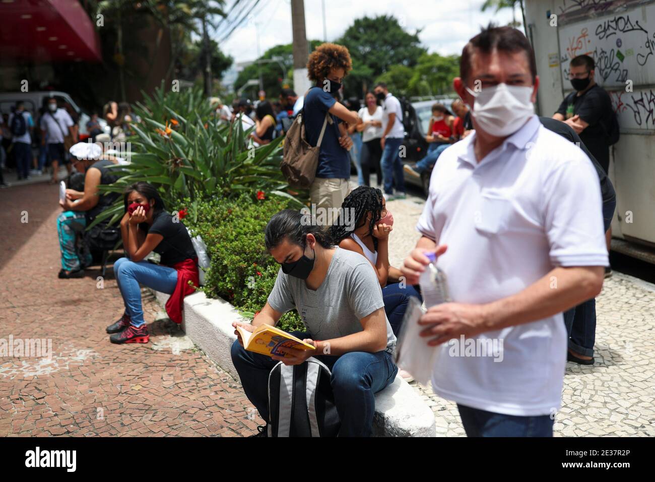 A man reads a book as people gather before the beginning of the ENEM, Exame Nacional do Ensino Medio (National High School Exam), during the outbreak of the coronavirus disease (COVID-19), at UNIP Vergueiro test site in Sao Paulo, Brazil January 17, 2021. REUTERS/Amanda Perobelli Stock Photo