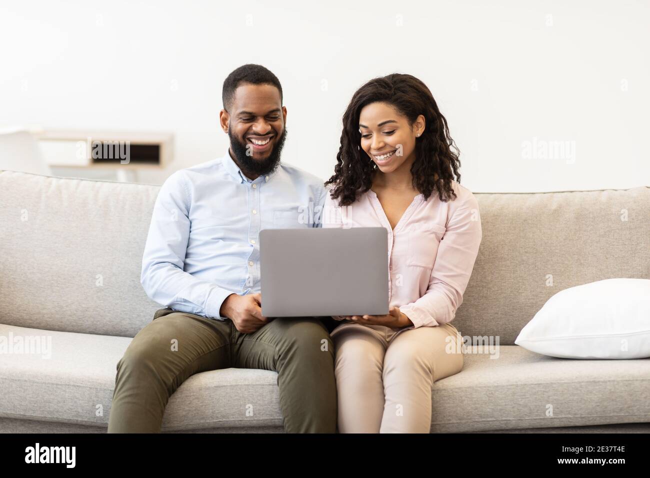 African american couple sitting on couch, using laptop computer Stock ...