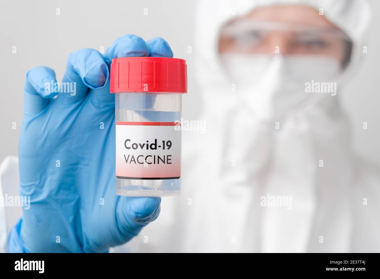 Developing and testing of Covid 19 vaccine. Doctor in protective suit, face mask, safety googles and rubber gloves demonstrate vaccine against Stock Photo