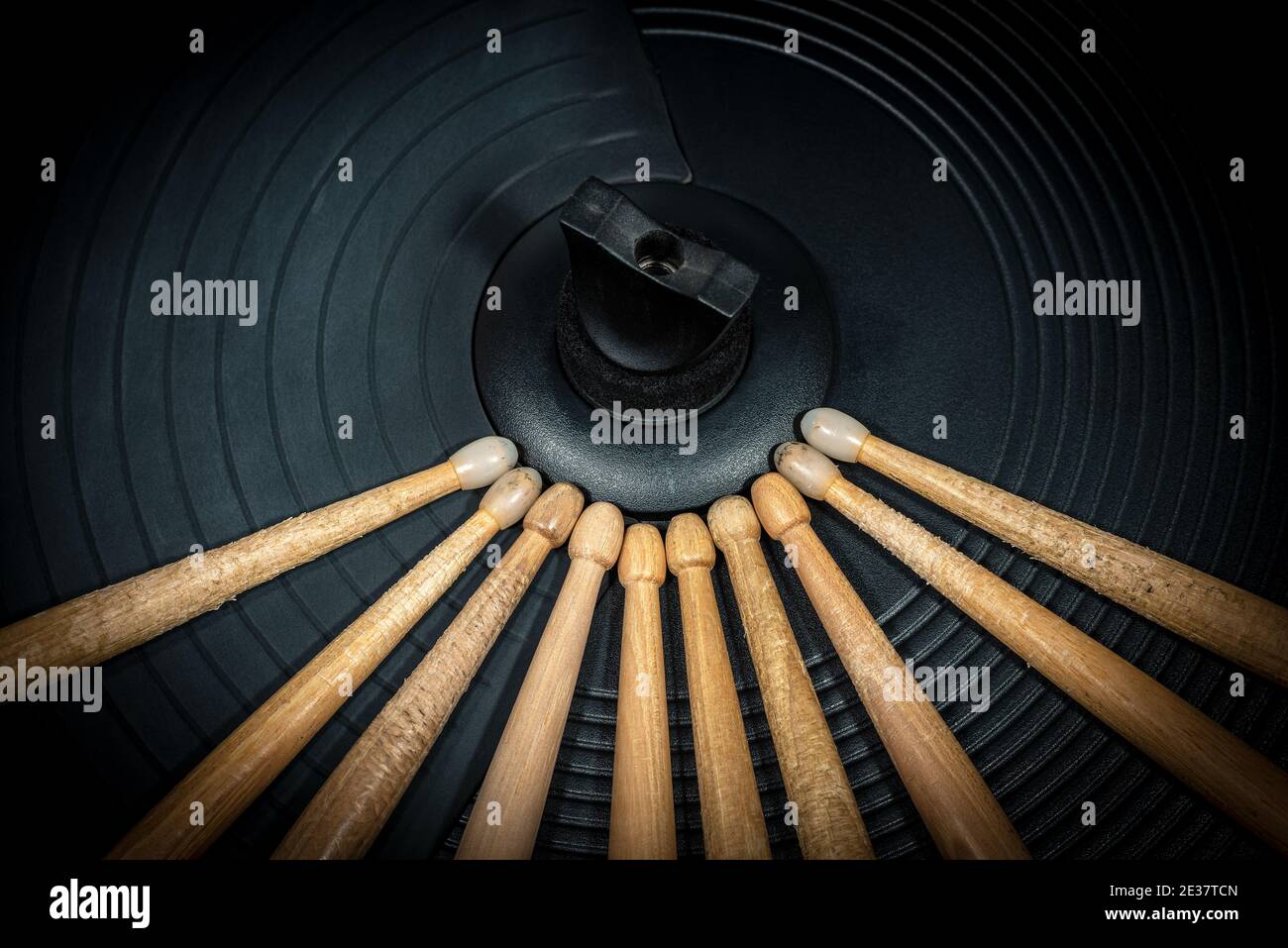 Extreme closeup of a group of wooden drumsticks on a black cymbal of an