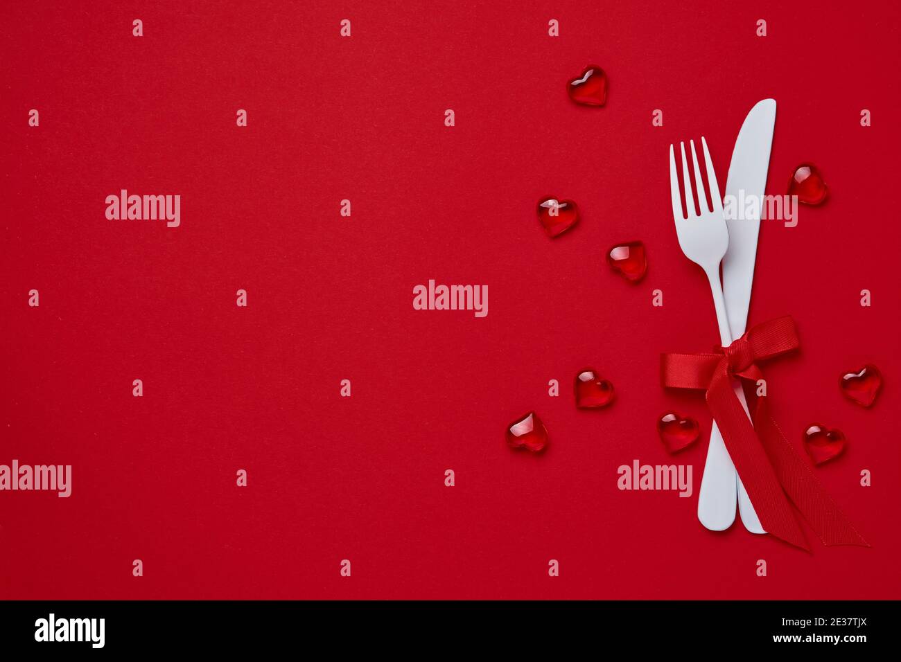 Valentines day background or concept with empty white plate, small heart-shaped plate with small hearts inside and whiteware on scarlet or red backgro Stock Photo